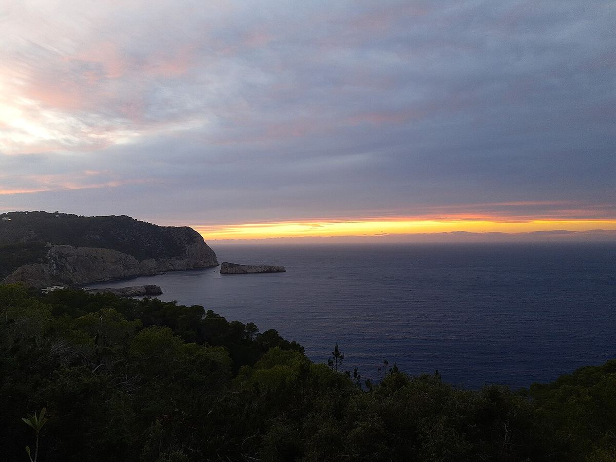 Puesta de sol sobre el mar desde la costa occidental de Ibiza con acantilados a la izquierda