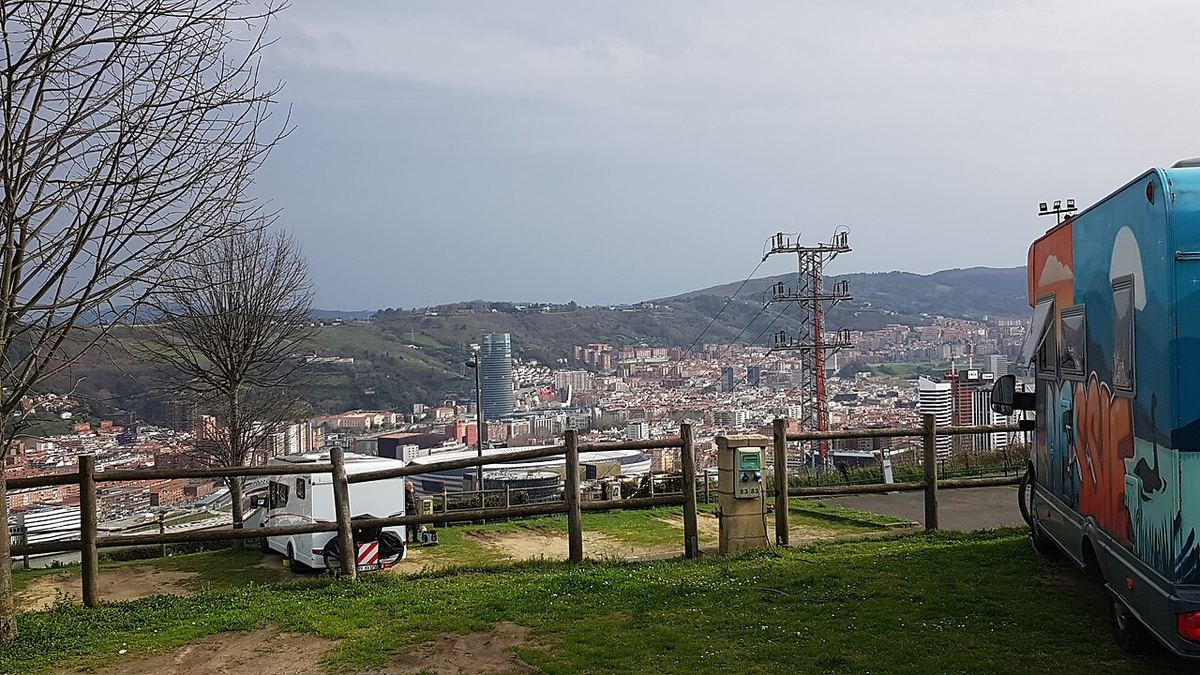 Autocaravanas aparcadas en un área elevada con vistas a una ciudad y montañas