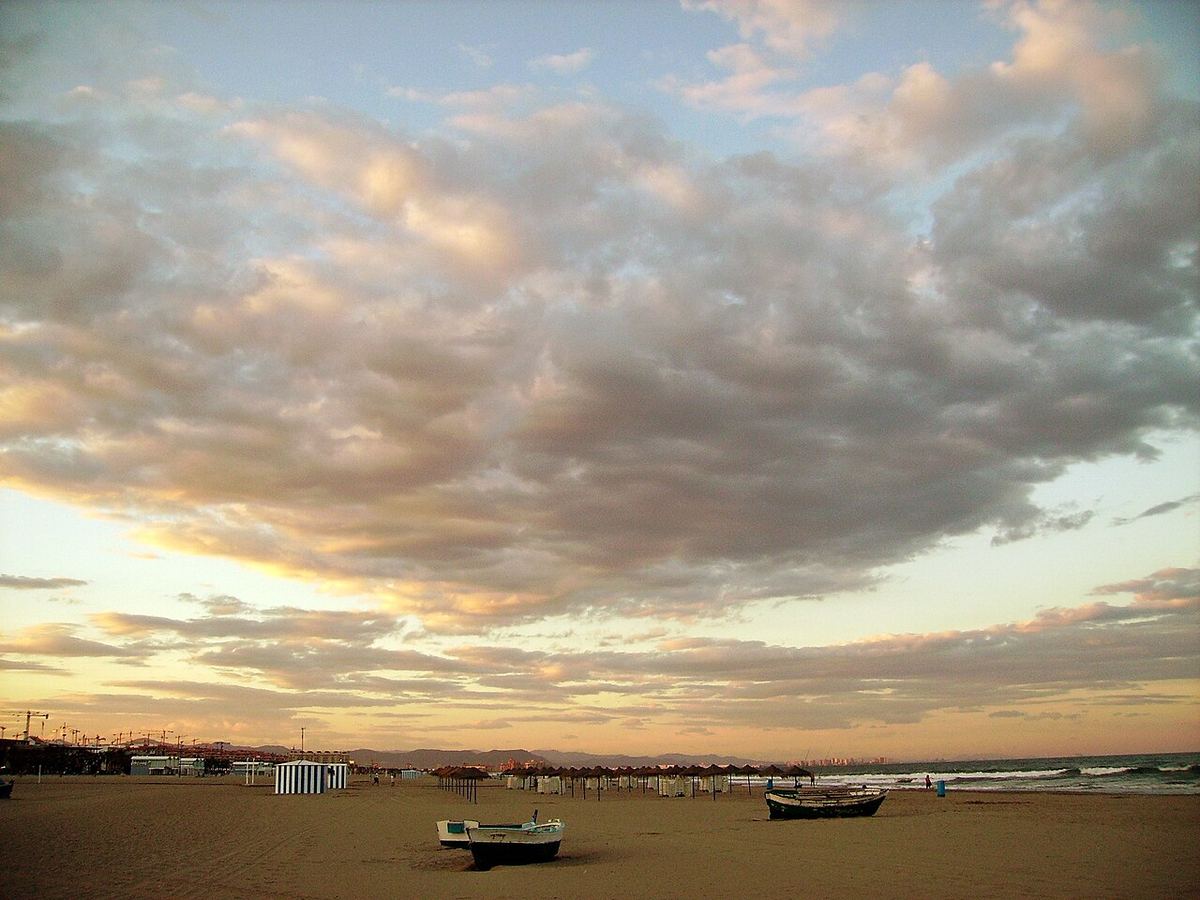 Playa de la Malvarrosa en Valencia al atardecer con barcas en la arena
