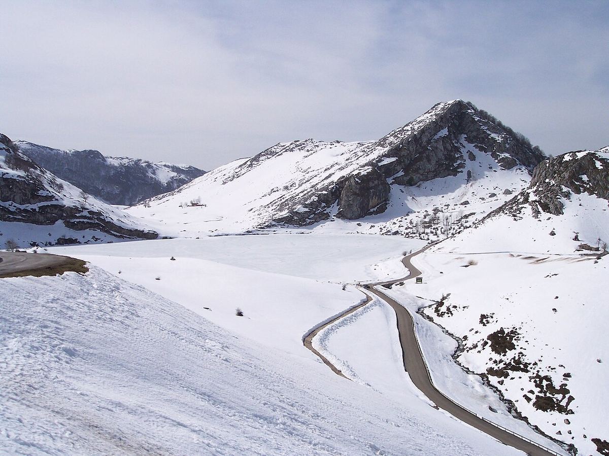 Carretera de montaña serpenteando entre laderas nevadas en los Picos de Europa